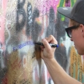 Tourist defacing the John Lennon Peace Wall with horrid graffiti